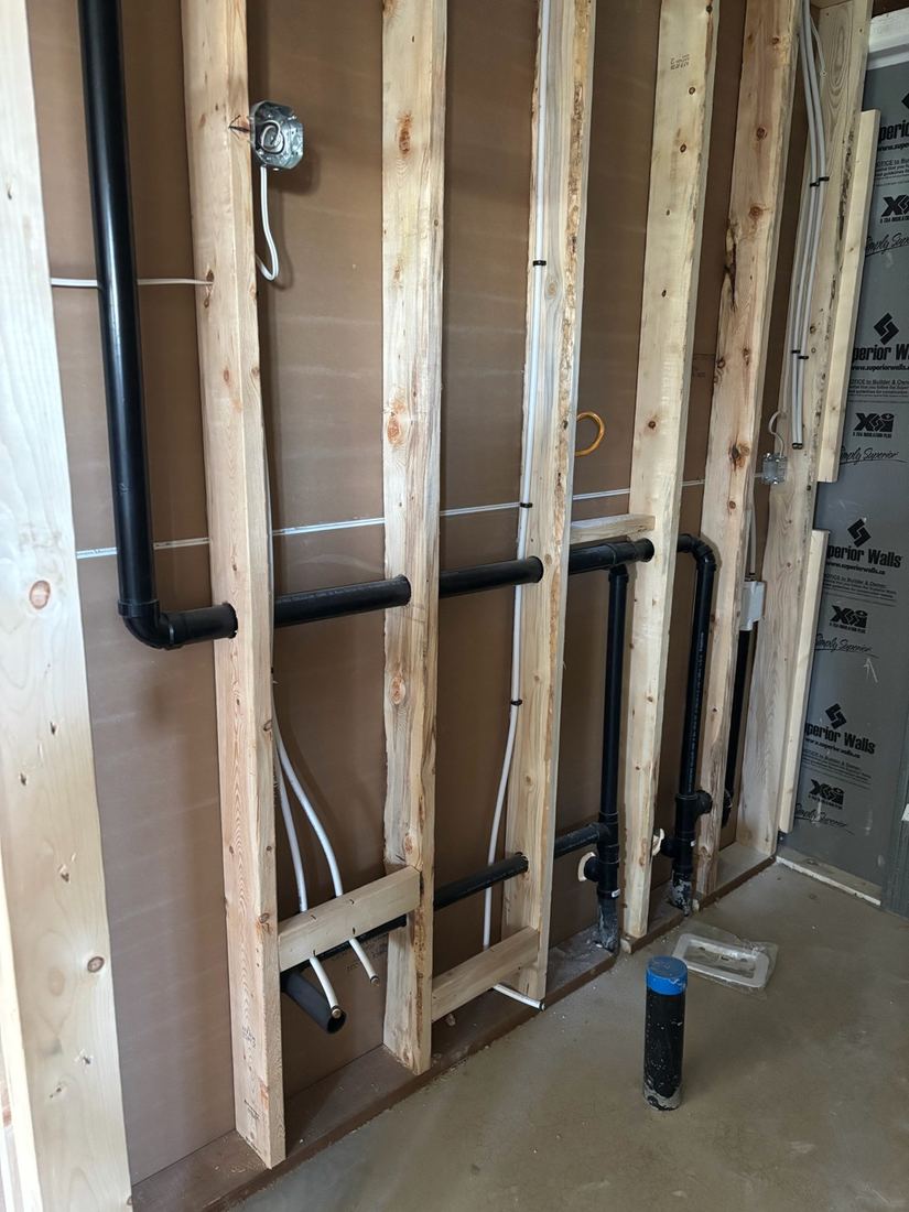 Black drain pipes roughed in between wood wall studs