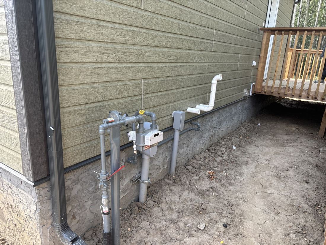 Gas meter and service piping on the outside wall of a house