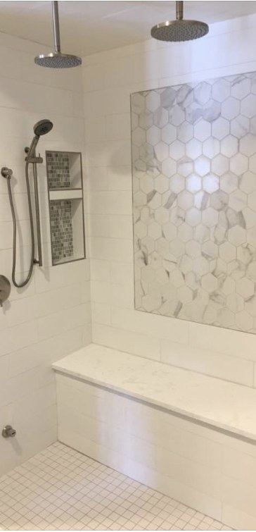 Tiled walk-in shower with two overhead shower heads, a hand shower, a niche and a bench